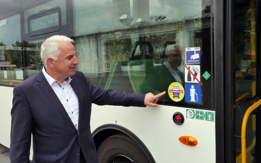 Rainer Deppe zeigt auf einen Aufkleber am Bus, der einen Abbiegeassistenten eingebaut hat